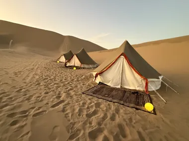 White canvas tents on the dune at golden hour