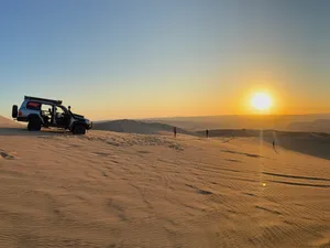 The dunes end to end, a buggy parked at the rim